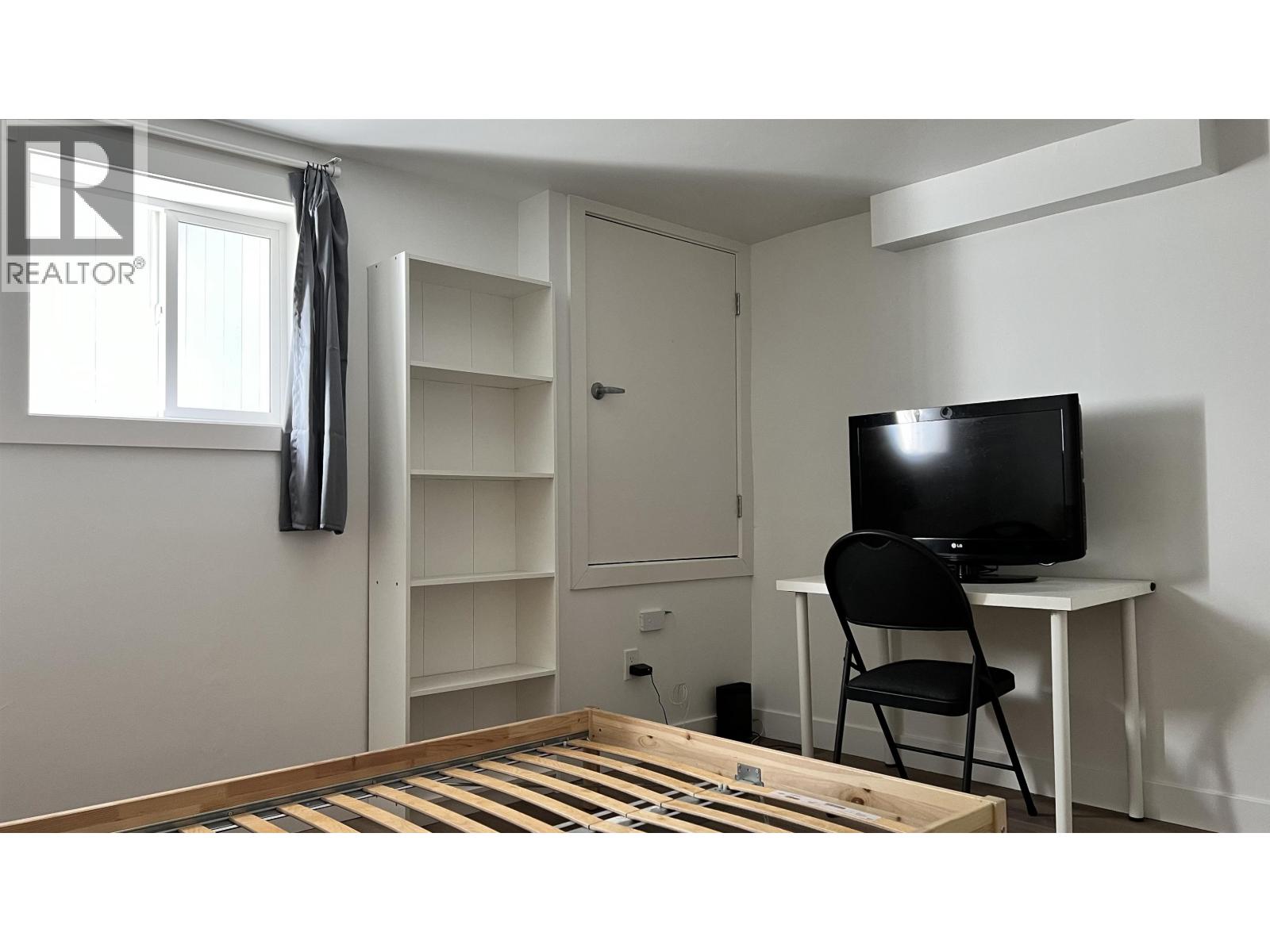 A room with a black chair and a black television on a white table.