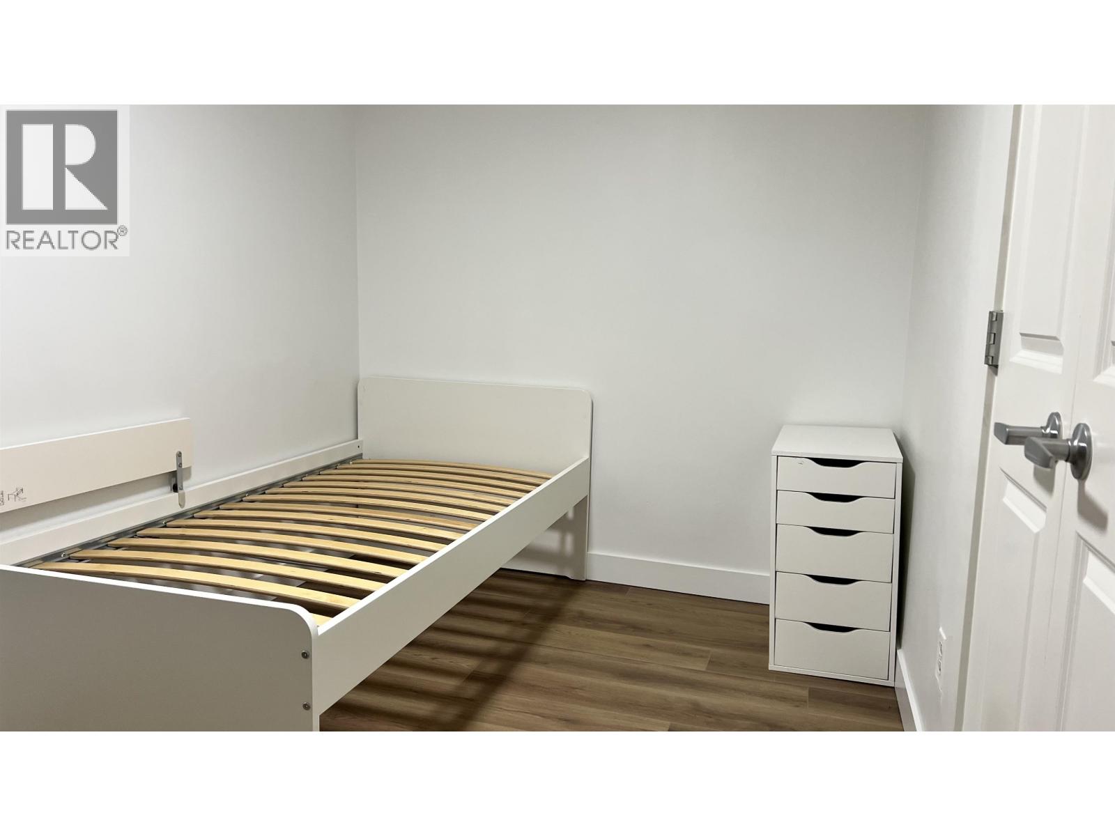 A bedroom with a bed, nightstand and a cabinet.