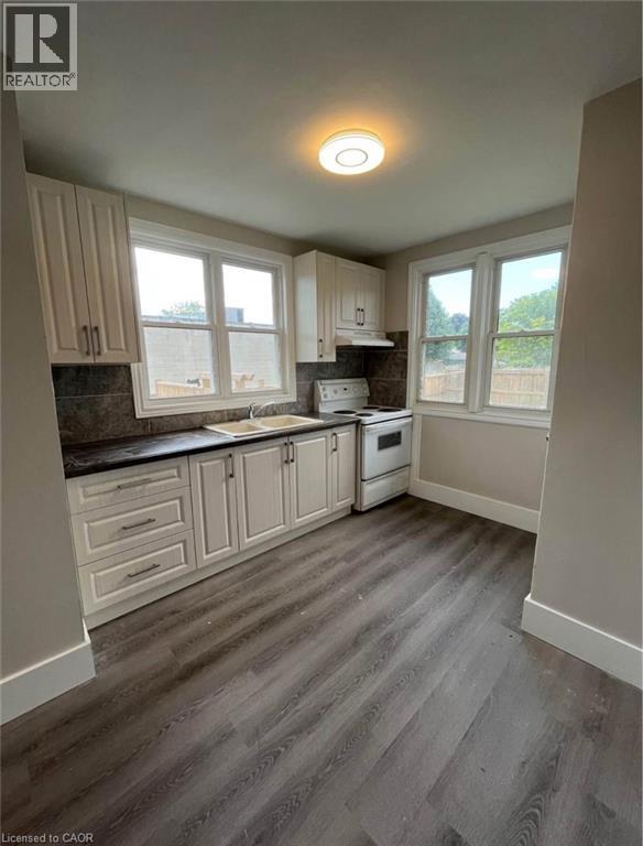 A kitchen with wooden floors and white cabinets.