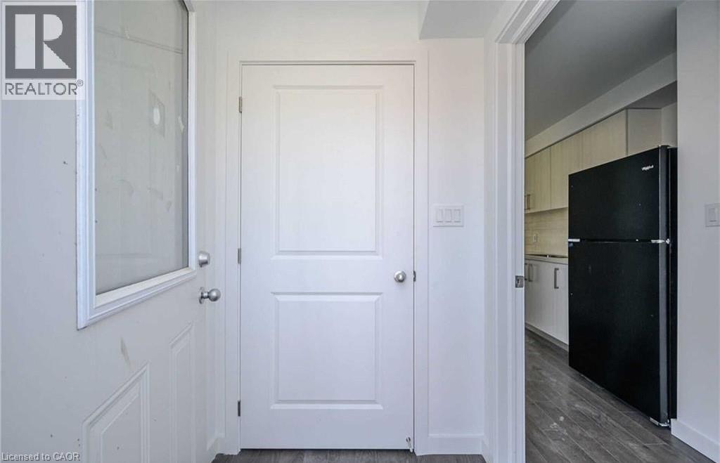 A black refrigerator is in a kitchen with white walls.