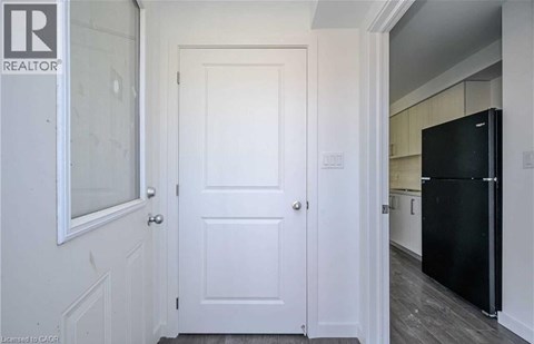 A black refrigerator is in a kitchen with white walls.