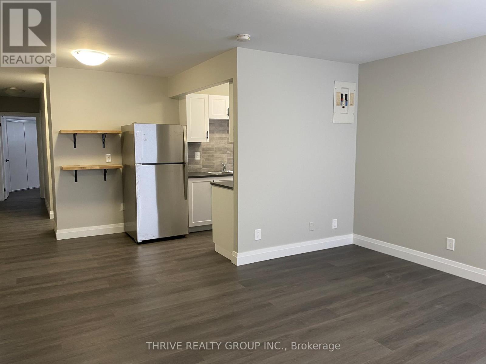 A kitchen area with a refrigerator, cabinets, and a countertop.