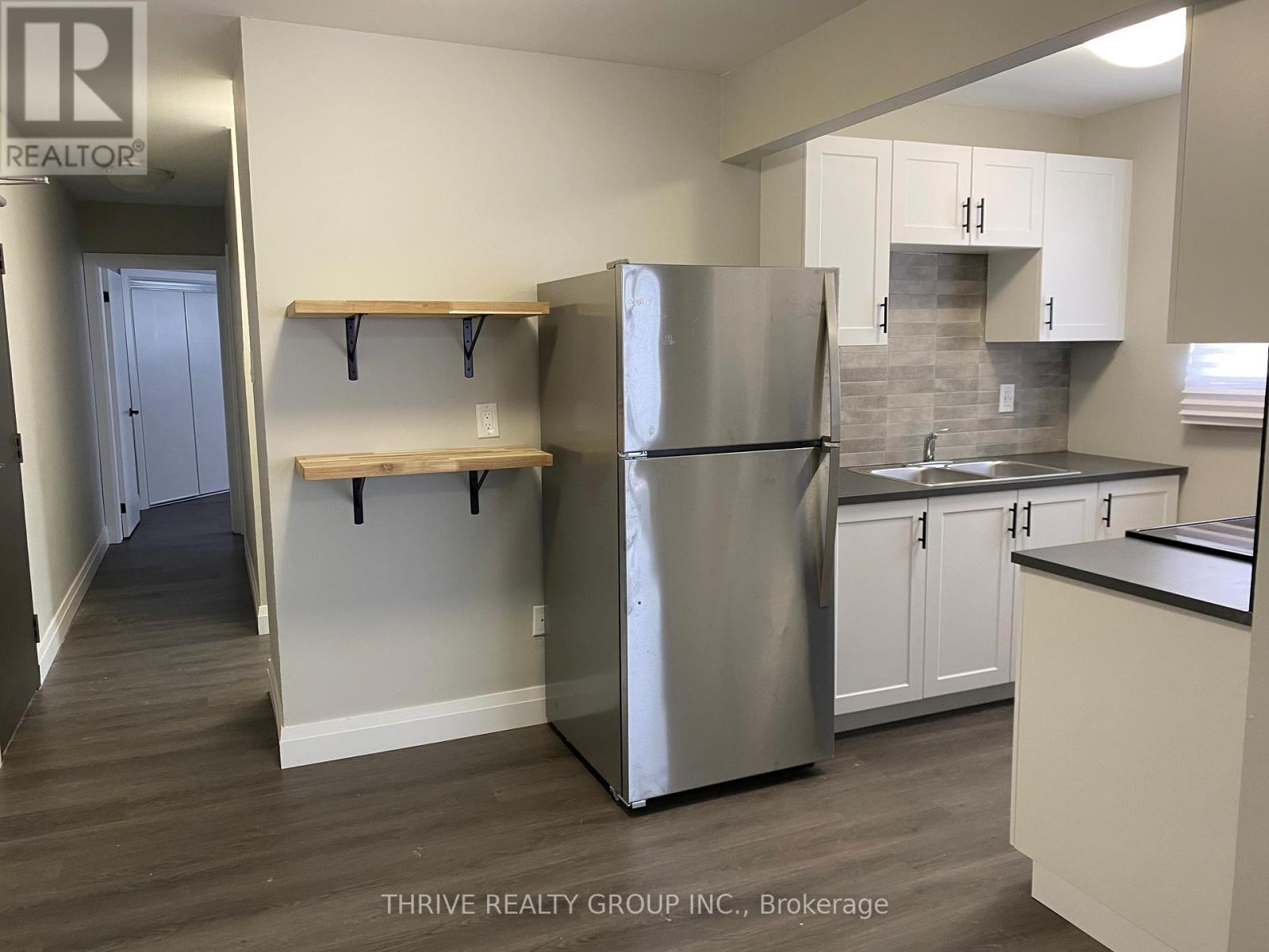 A kitchen with a refrigerator, cabinets, and a counter.