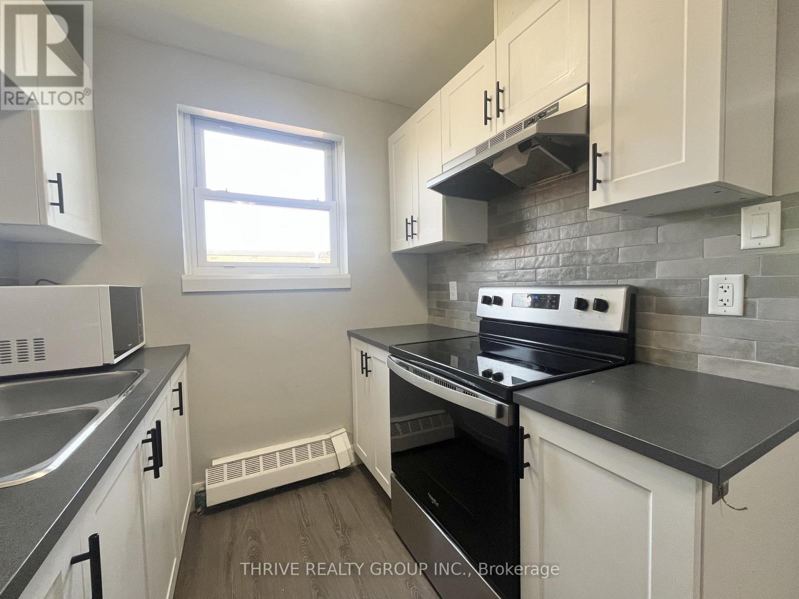 A kitchen with white cabinets and a black stove top oven.