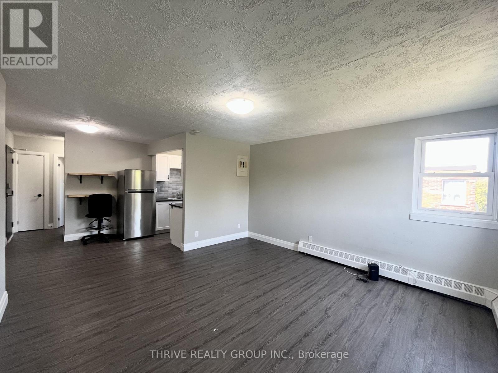 A room with wood flooring and a window on the right side.