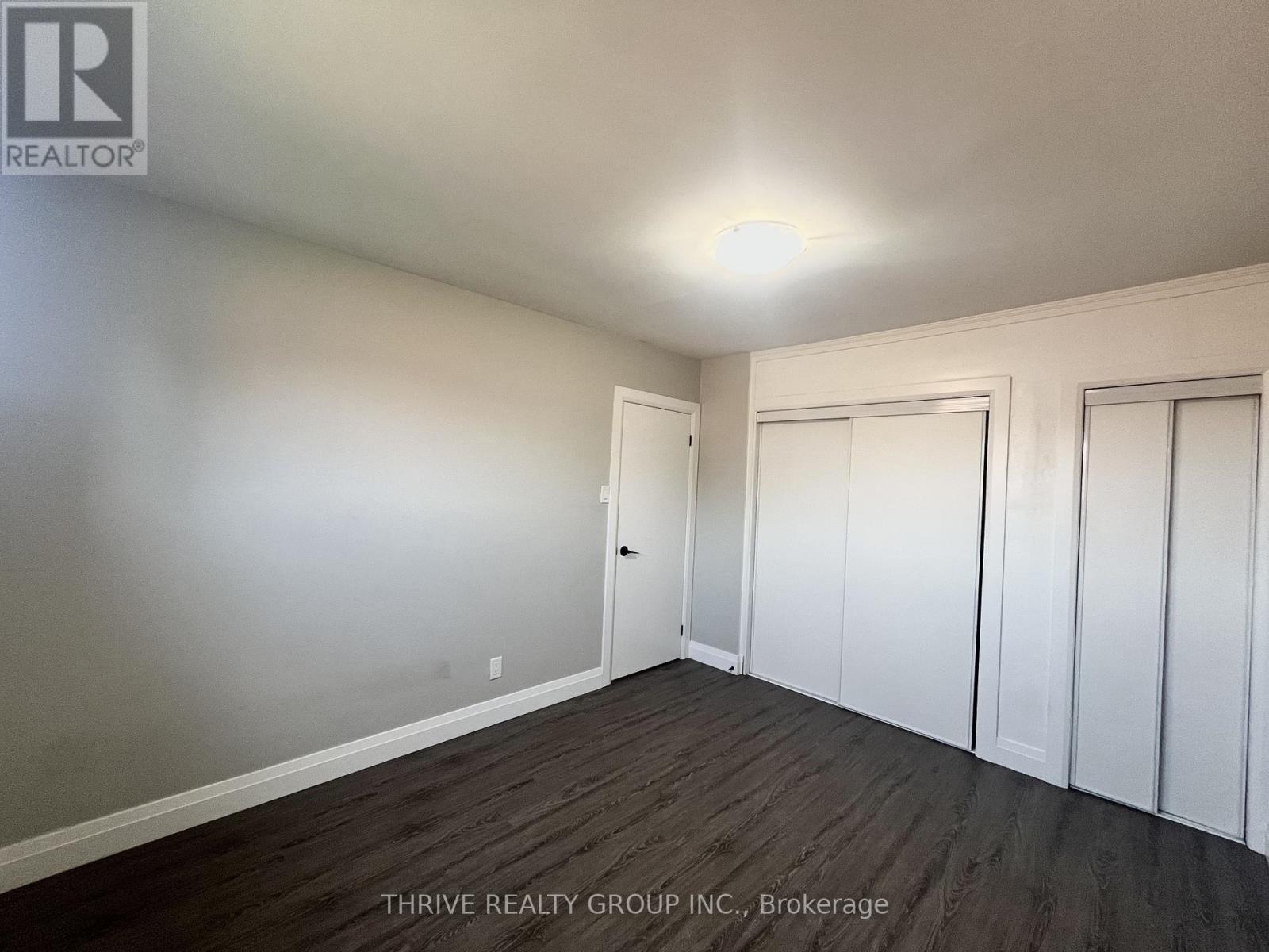 A room with a door and a window with a white wall and a wooden floor.