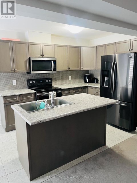 A kitchen with a black refrigerator and a granite countertop.