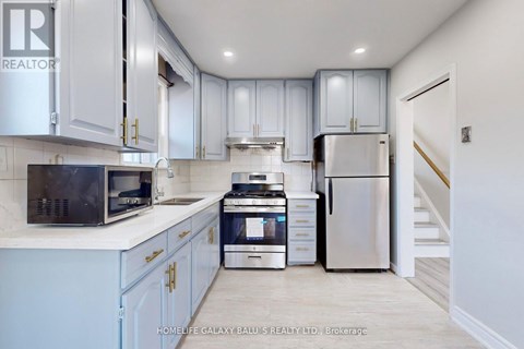 A kitchen with white cabinets and a stainless steel refrigerator.