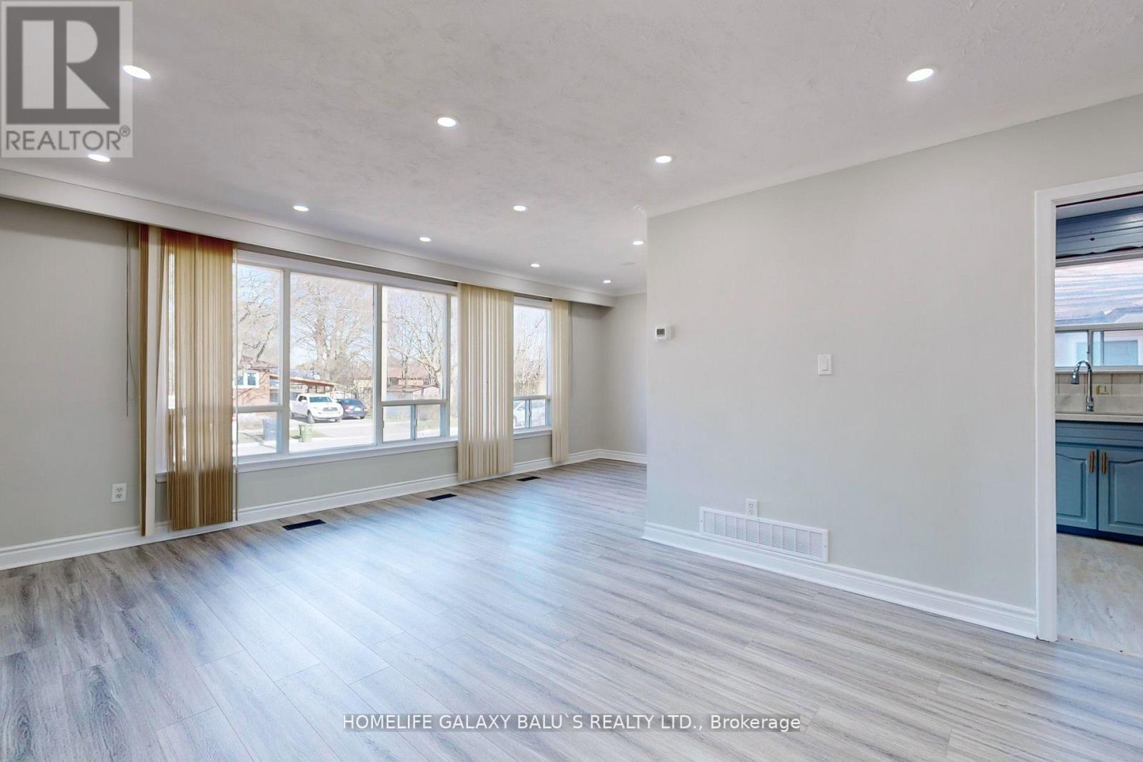 A spacious room with wood flooring and large windows.