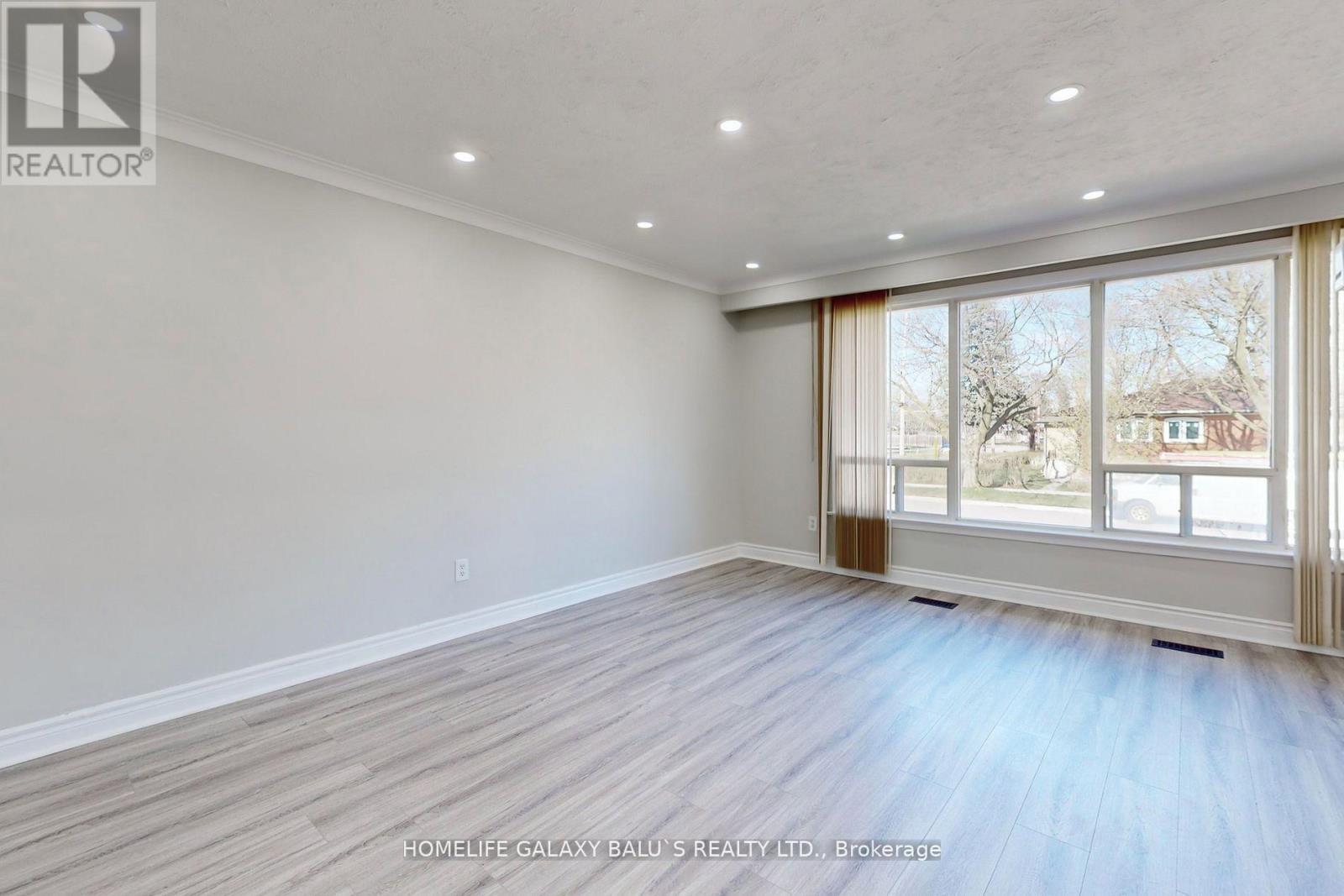 A room with a large window and wooden flooring.