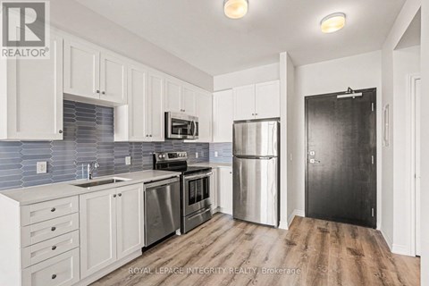 A kitchen with white cabinets and a black refrigerator.