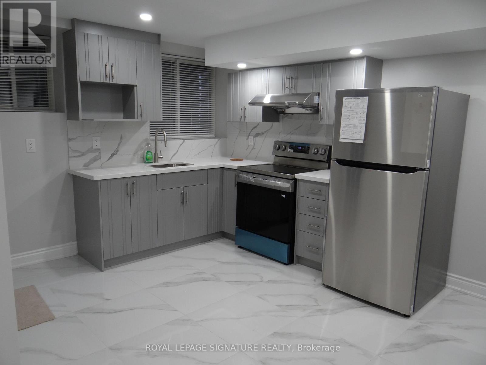 A modern kitchen with stainless steel appliances and marble flooring.
