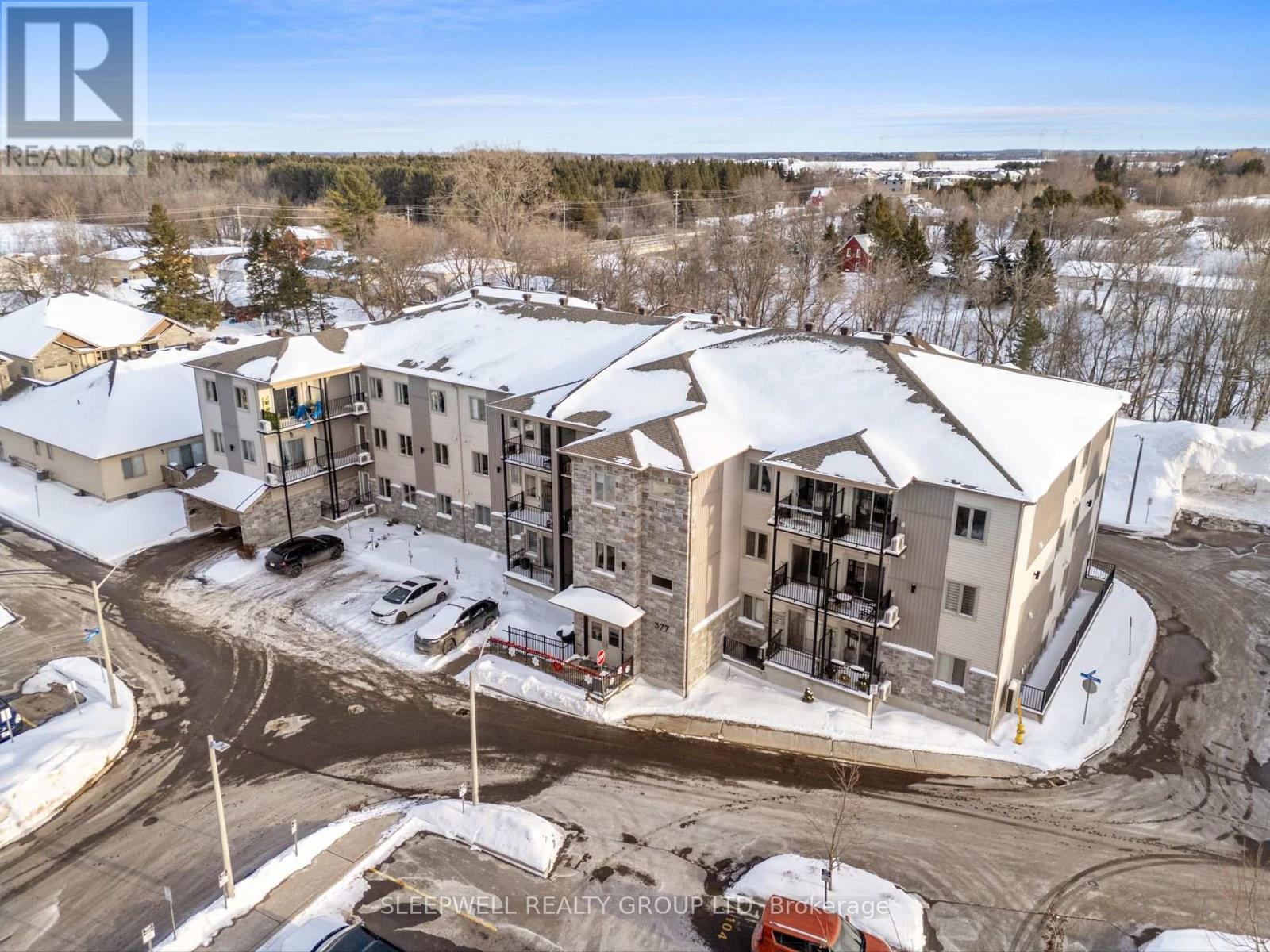 A real estate group photo of a building with snow on the ground and trees in the background.