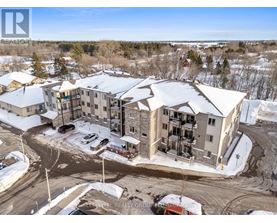 A real estate group photo of a building with snow on the ground and trees in the background.