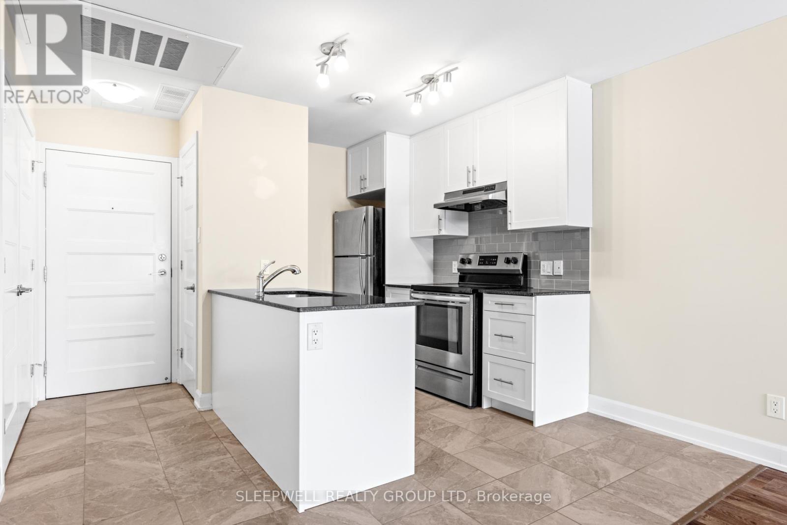 A kitchen with white cabinets and a black countertop.