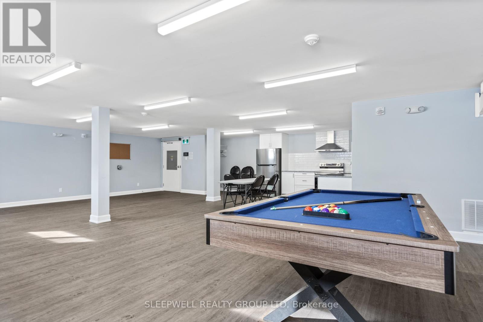 A pool table is in the middle of a room with a Sleepwell Realty Group logo.