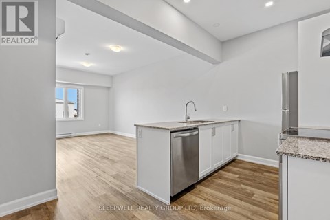A kitchen with white cabinets and a wooden floor.