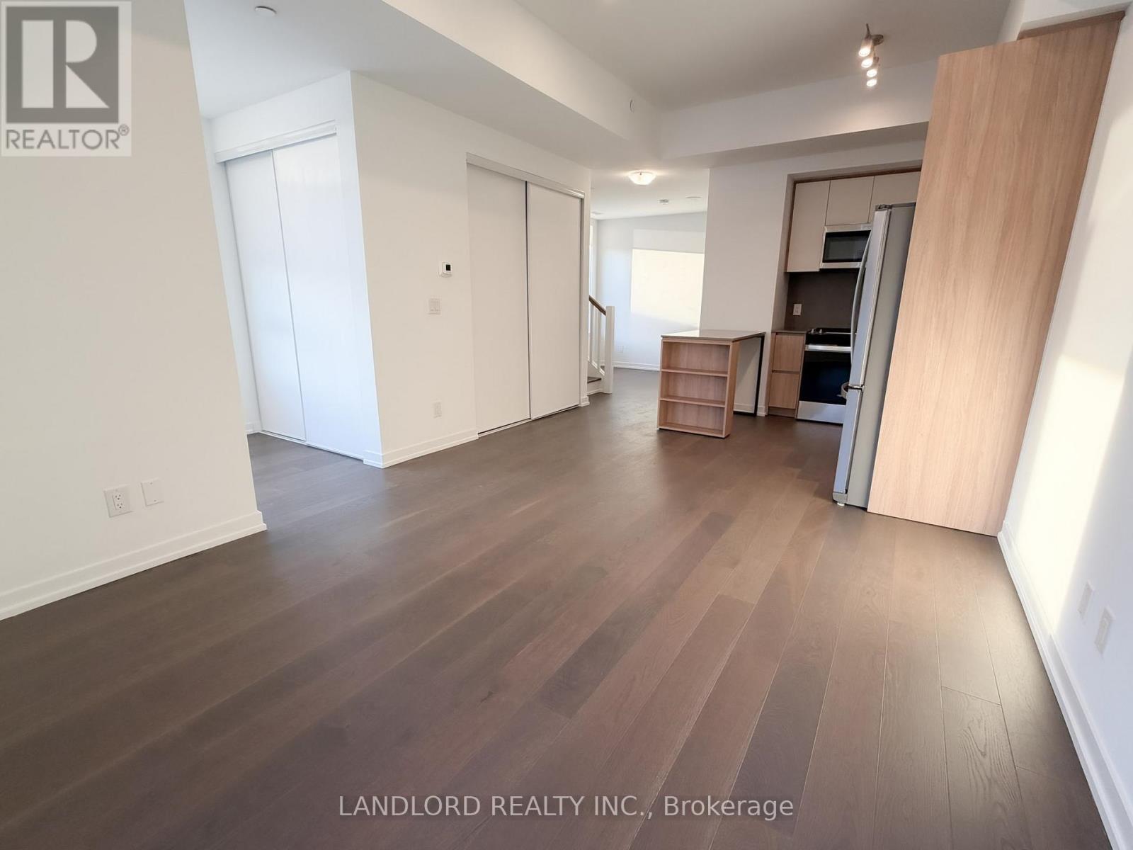 A spacious room with wooden flooring and white walls.