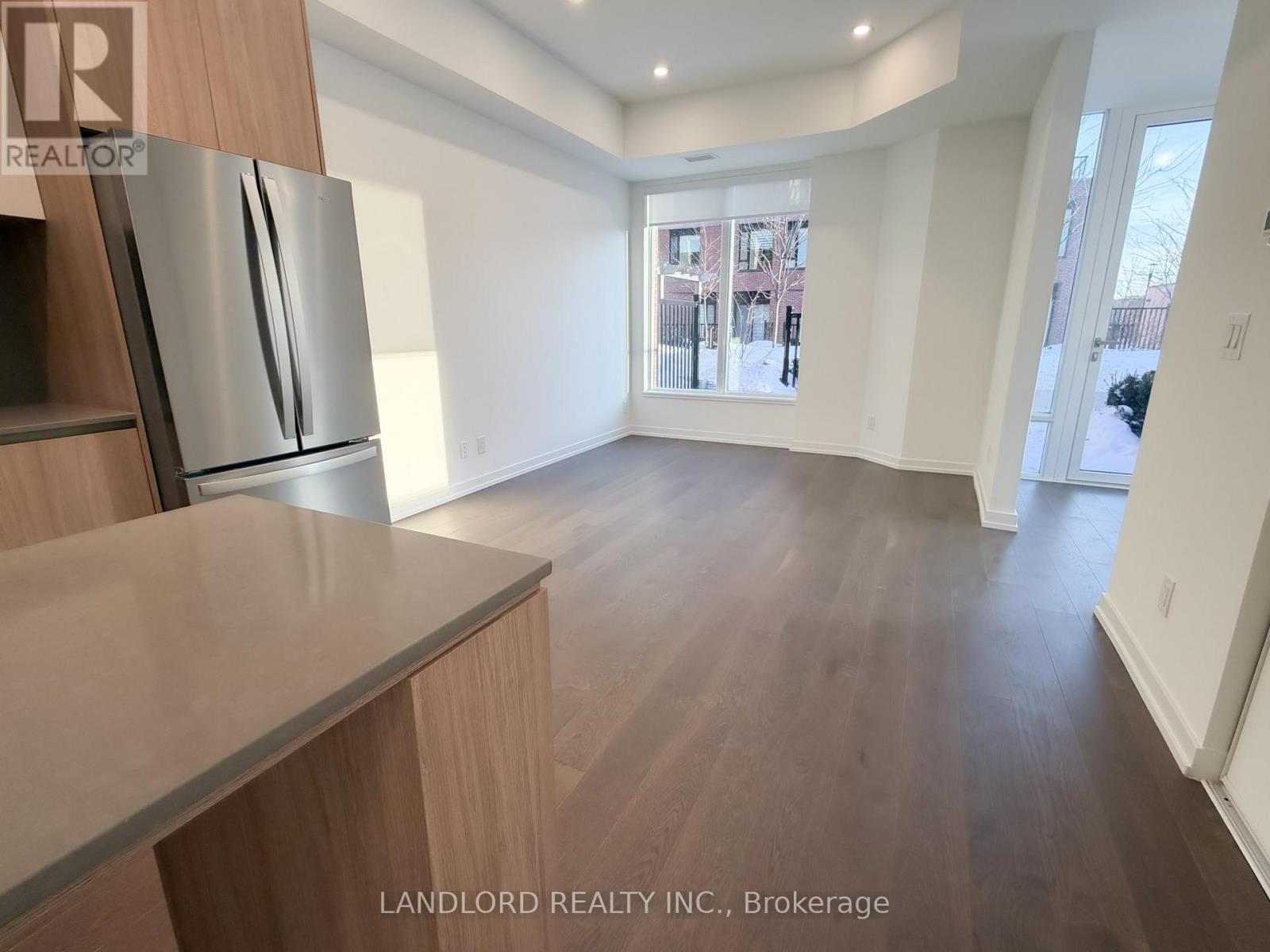 A kitchen with a refrigerator and wooden floors.