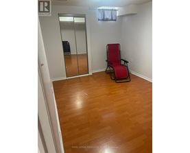 A room with a wooden floor and a red chair.