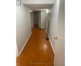 A hallway with a wooden floor and white walls.