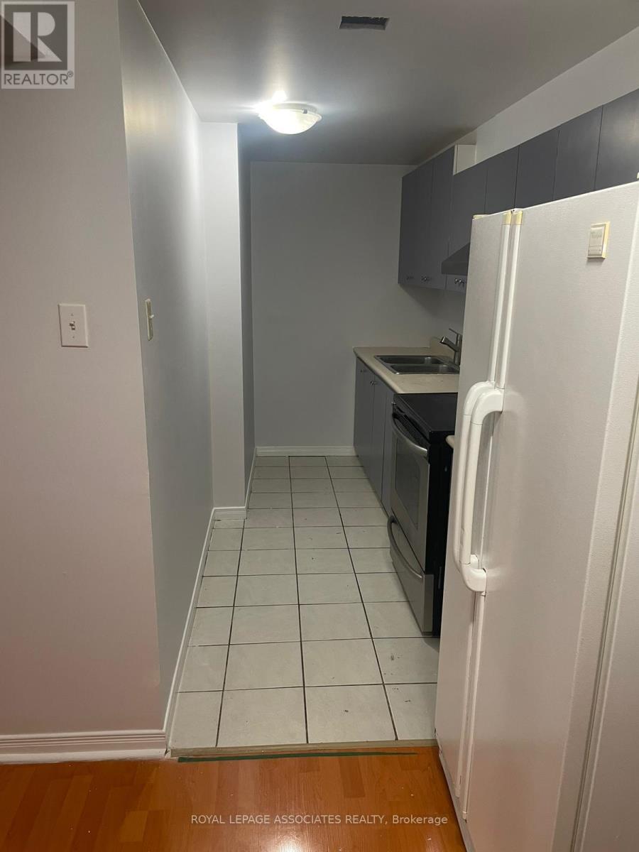 A white refrigerator is in a kitchen with white tile flooring.