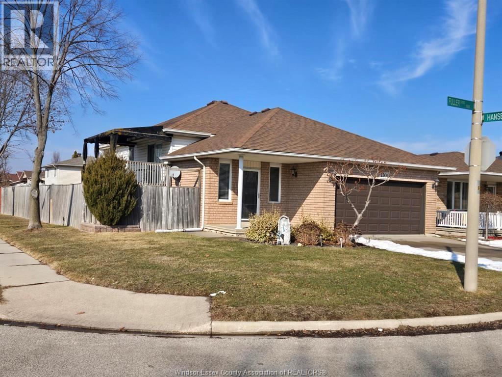 A house with a brown roof and a white fence is in front of a blue sky.