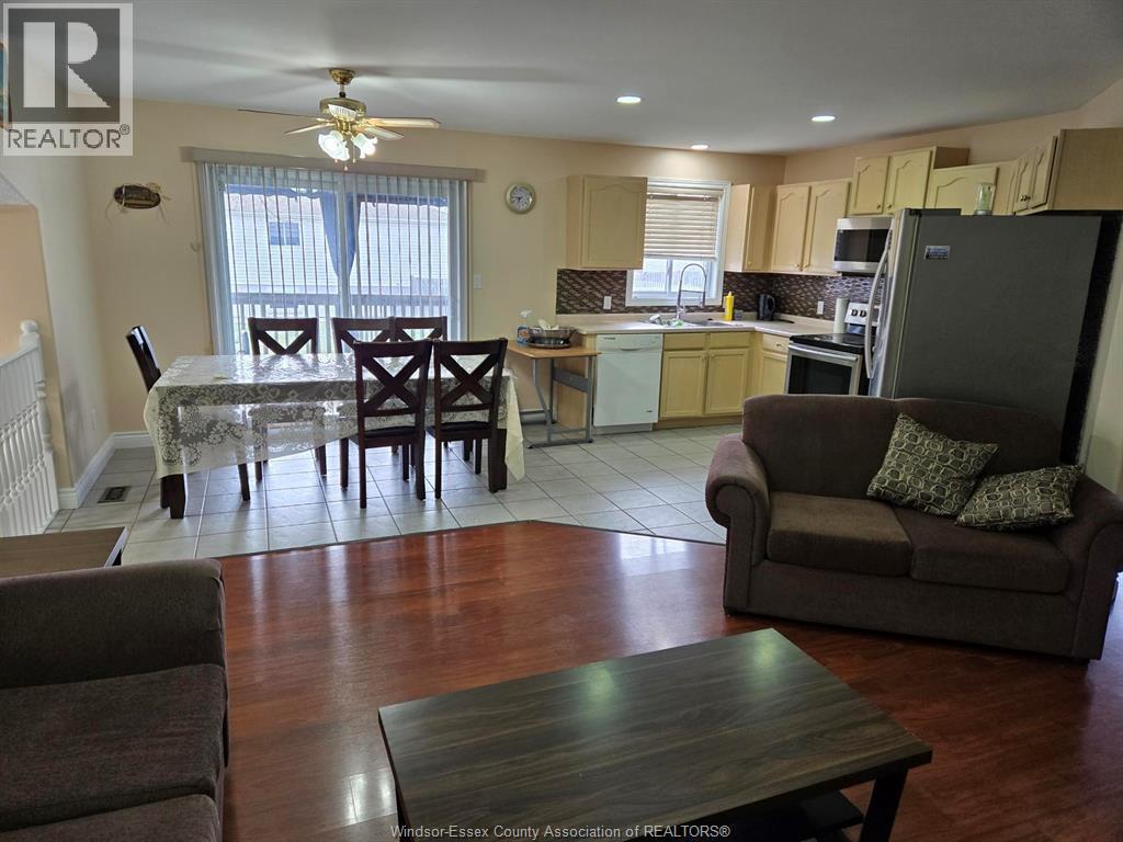 A living room with a brown couch and a dining table.