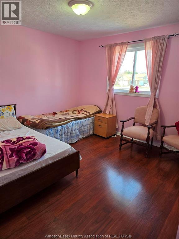 A bedroom with a bed, chair, and window.