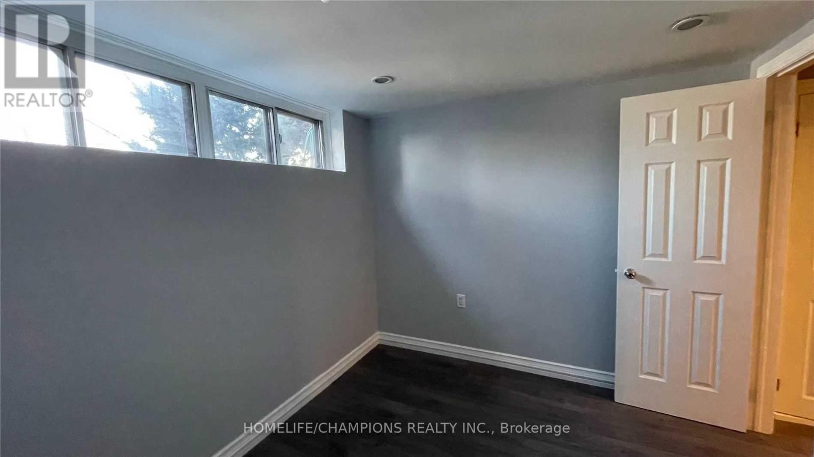 A room with a white door and a window with a view of trees.
