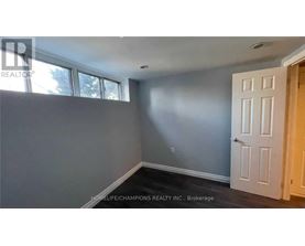 A room with a white door and a window with a view of trees.