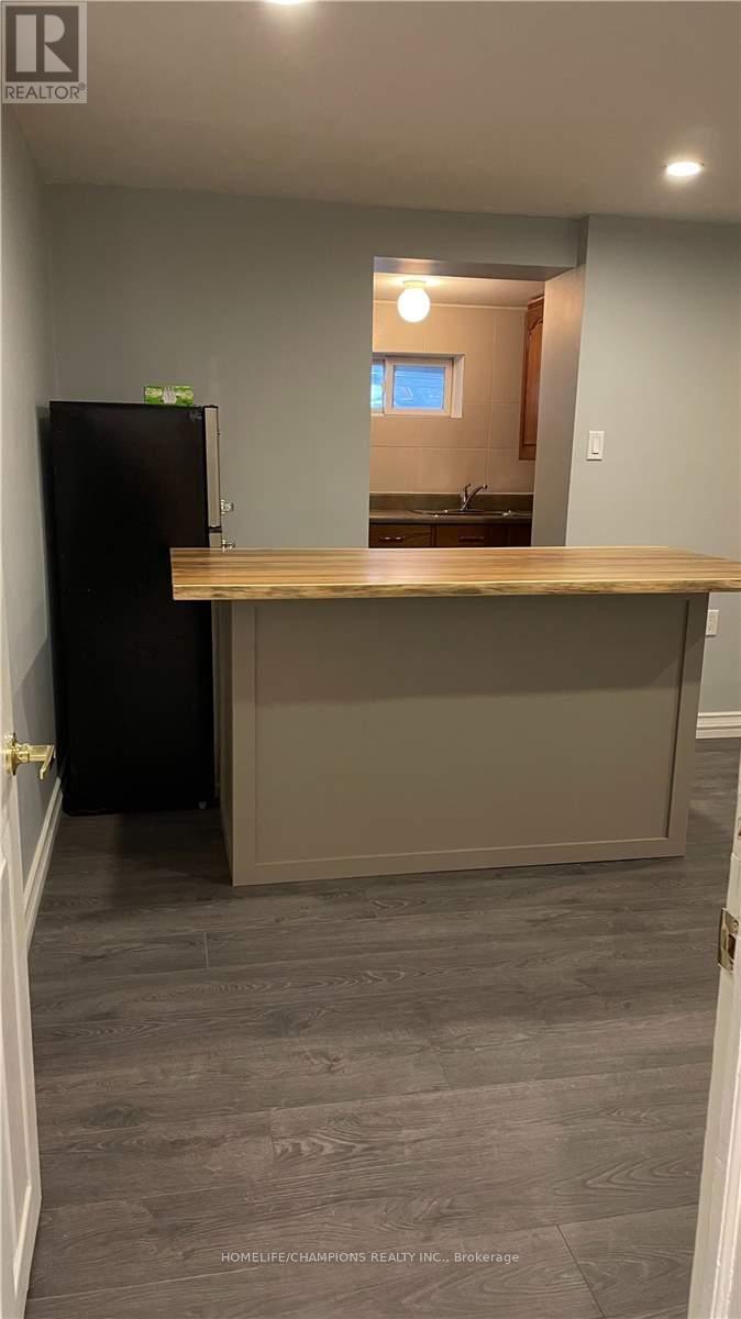 A kitchen with a black refrigerator and a wooden counter.
