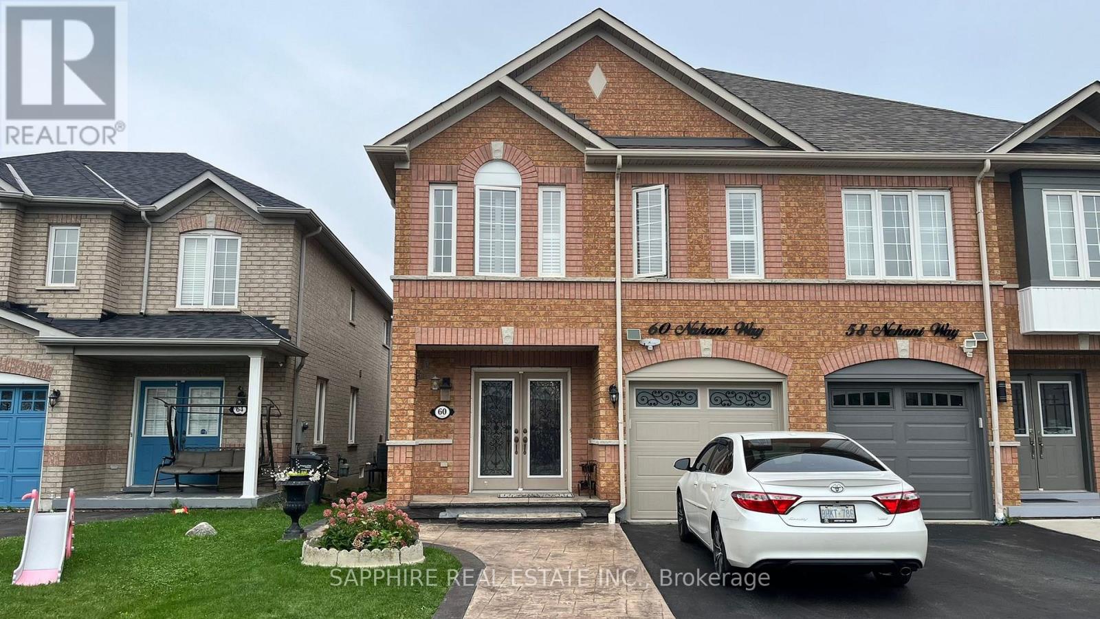A white car is parked in front of a brick house.