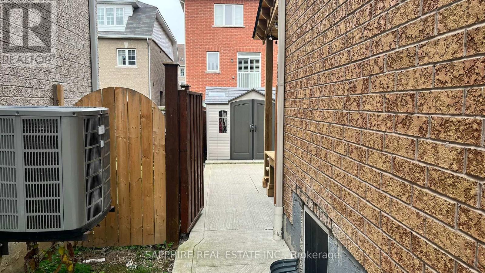A narrow alley with a brick wall on one side and a wooden fence on the other.