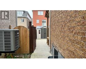 A narrow alley with a brick wall on one side and a wooden fence on the other.