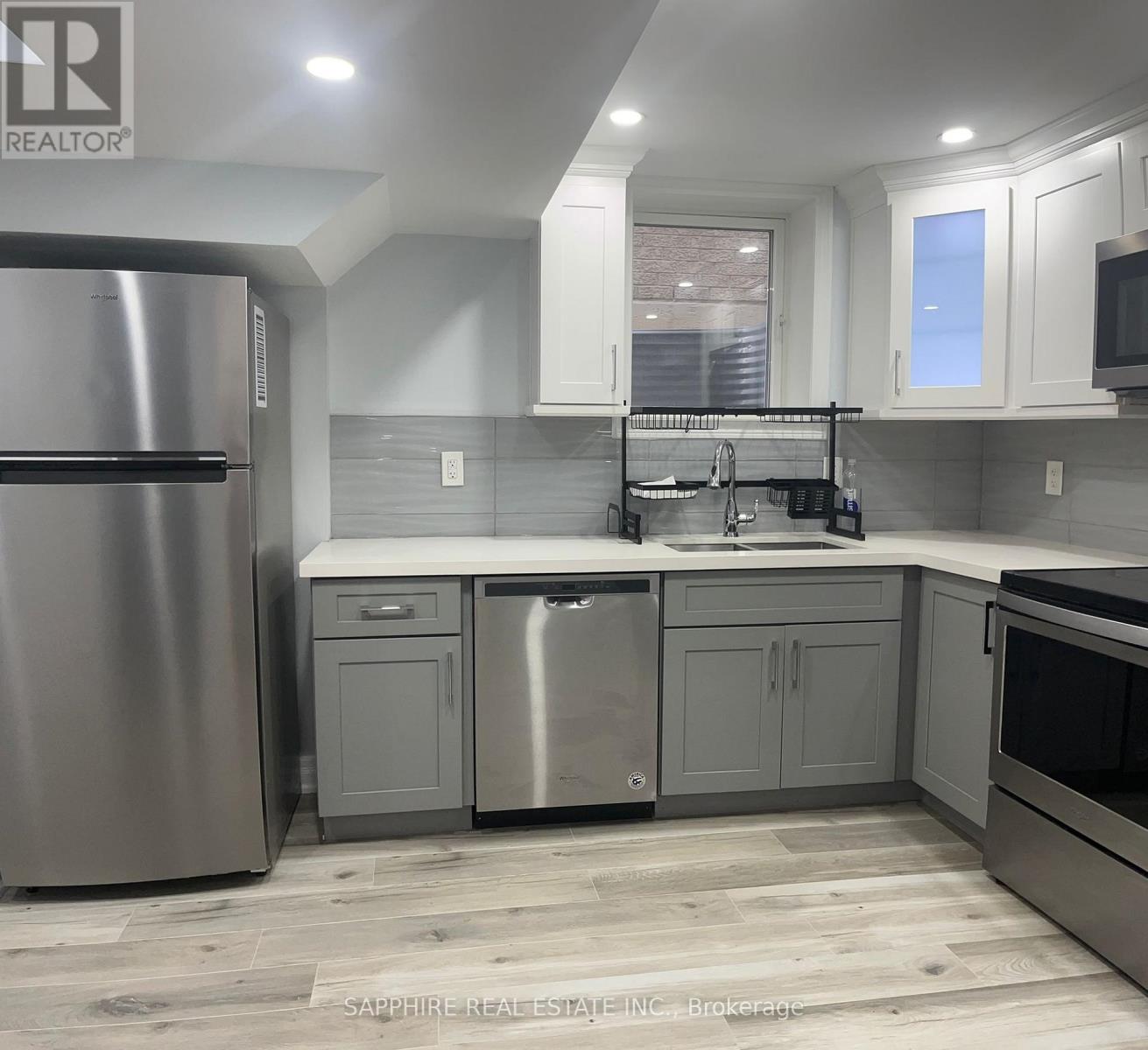 A modern kitchen with a stainless steel refrigerator and a double sink.