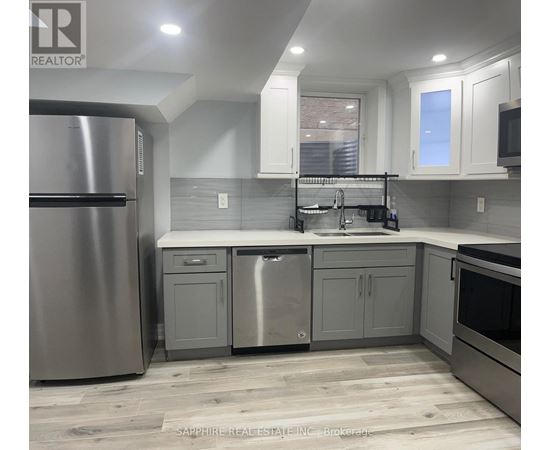 A modern kitchen with a stainless steel refrigerator and a double sink.