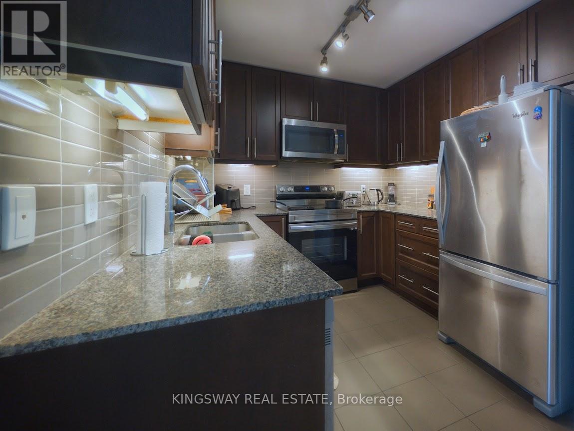 A kitchen with a refrigerator, microwave, and oven.