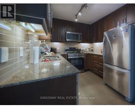 A kitchen with a refrigerator, microwave, and oven.