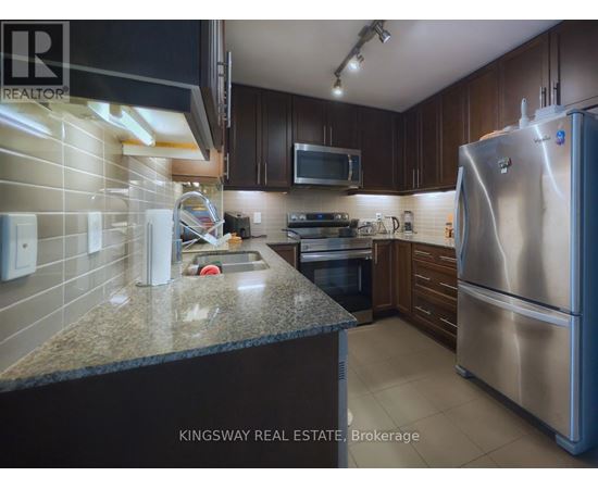 A kitchen with a refrigerator, microwave, and oven.