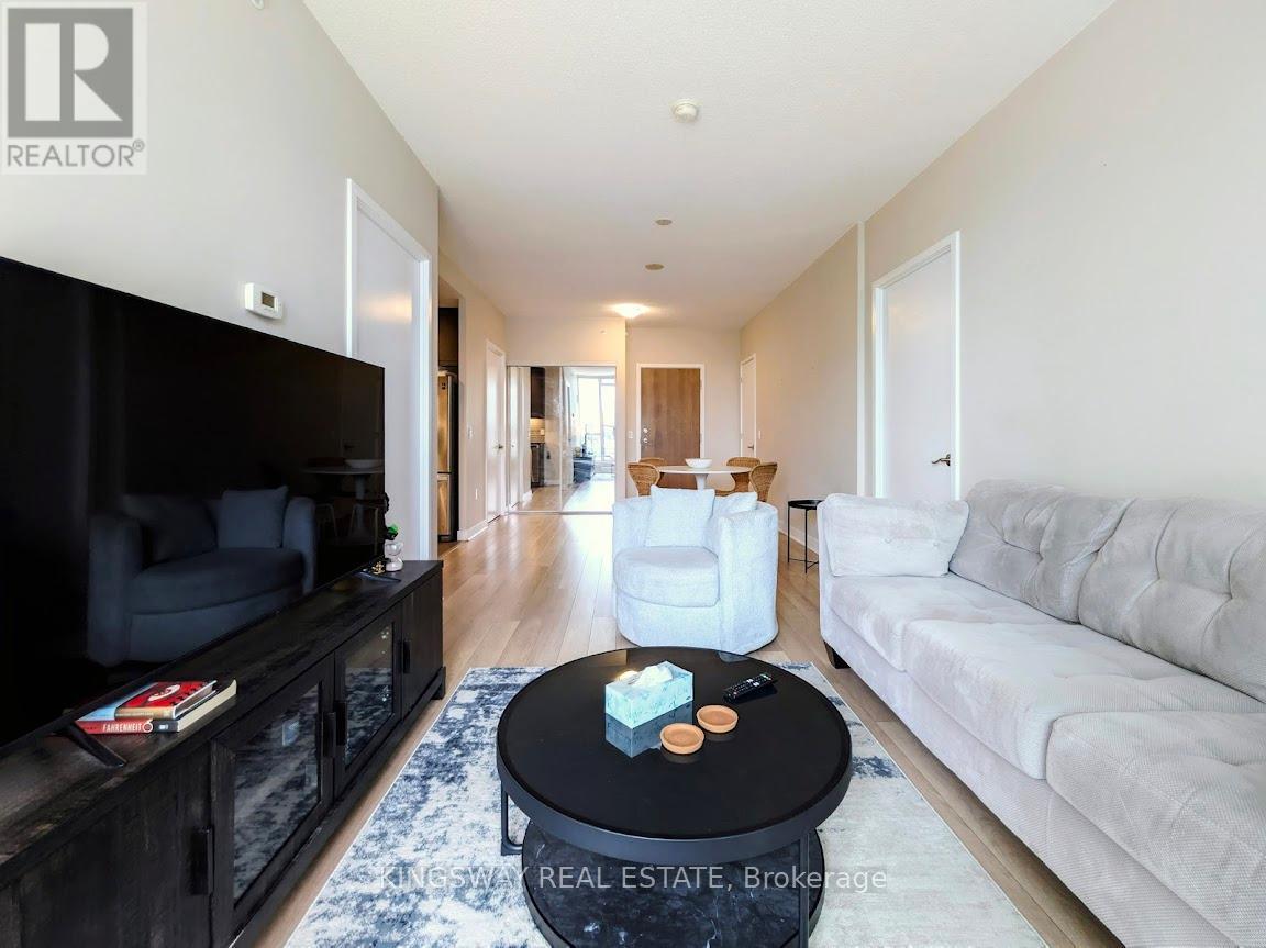 A living room with a black coffee table in the middle of a white couch and a black entertainment center.