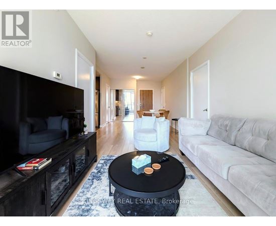 A living room with a black coffee table in the middle of a white couch and a black entertainment center.