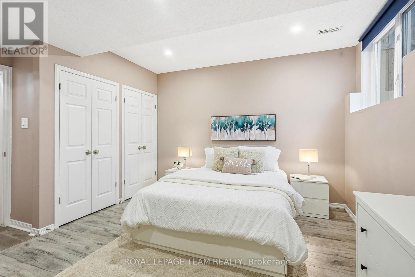 A bedroom with a large bed and a painting on the wall.