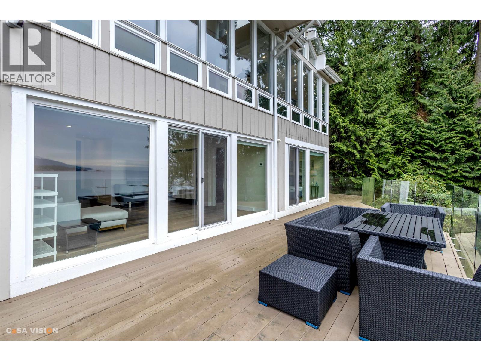 A patio with a table and chairs is in front of a building with a glass window.
