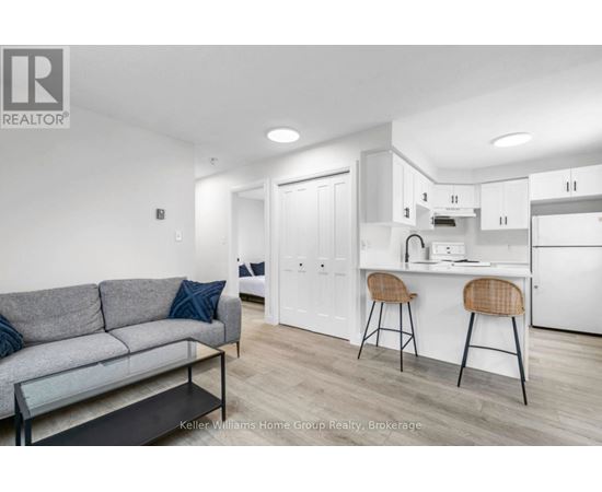 A modern living room with a grey couch and a kitchen area in the background.