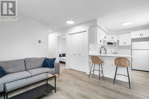 A modern living room with a grey couch and a kitchen area in the background.