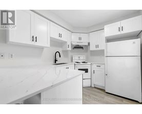 A white kitchen with a counter top and cabinets.