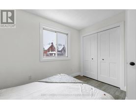 A bedroom with a large bed and a window overlooking a red house.