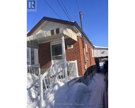A red brick house with a white porch and snow on the ground.