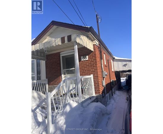 A red brick house with a white porch and snow on the ground.